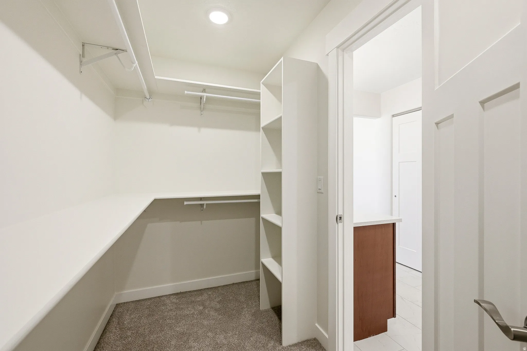 Walk-in closet featuring built-in shelving, hanging rods, and recessed lighting