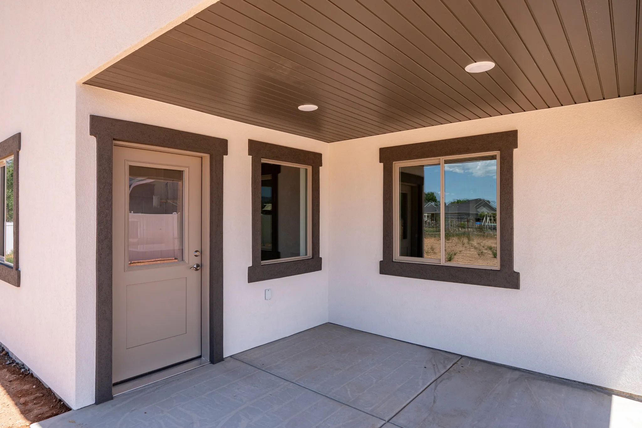 Covered patio featuring a concrete slab, recessed lighting, and a neutral-toned door with a glass insert