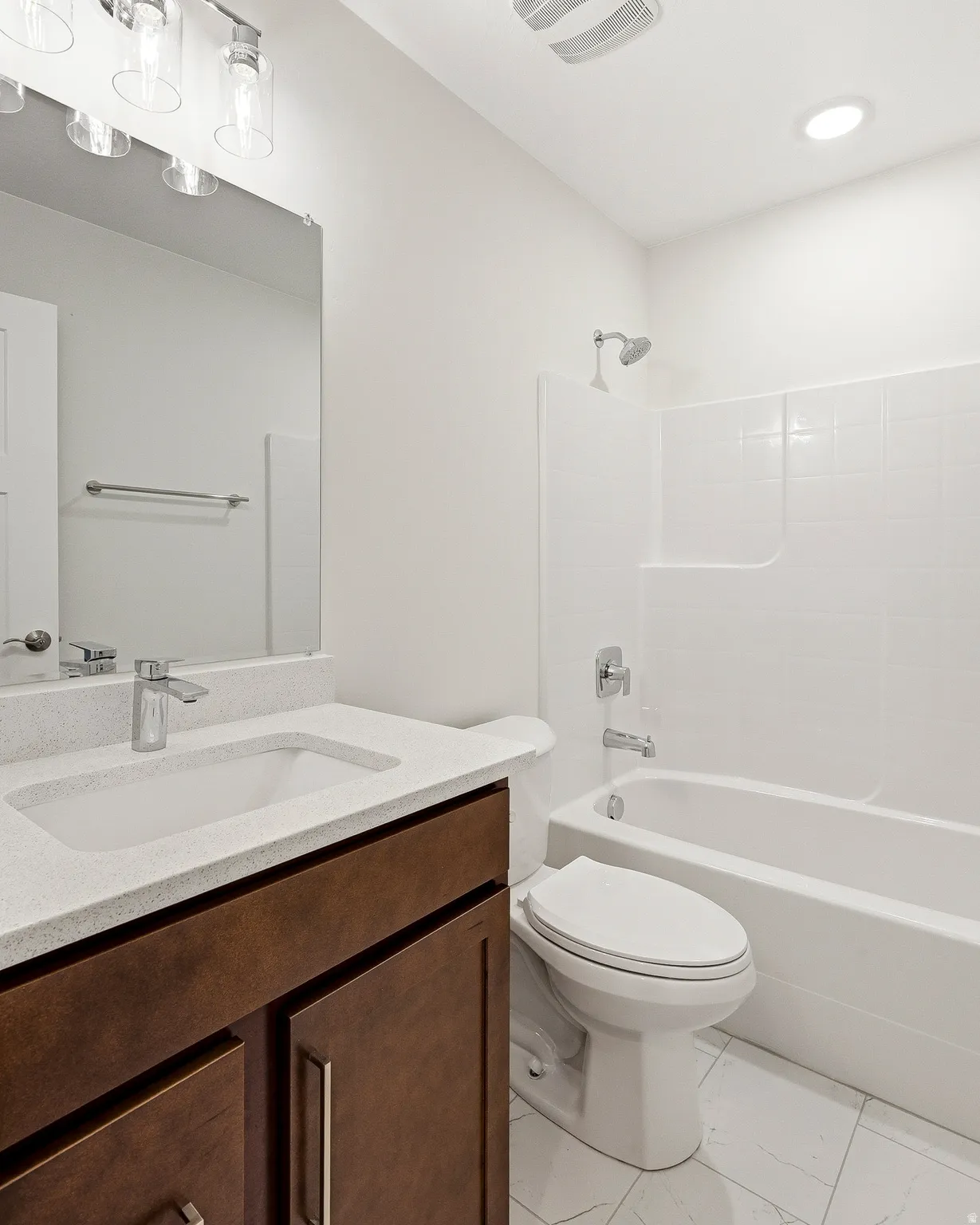 Vanity with a light-toned countertop, integrated sink, and wood-finish cabinetry