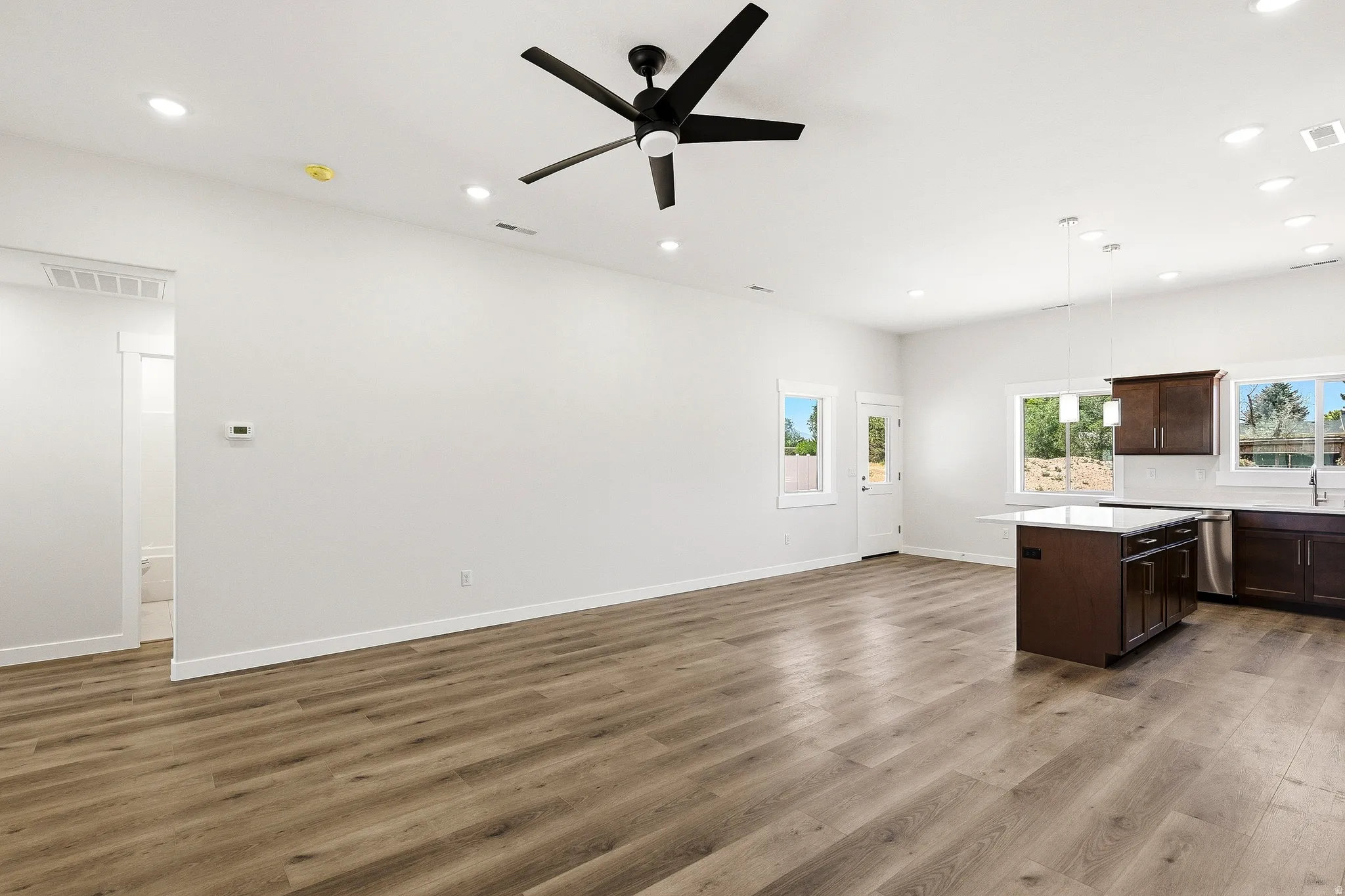Open-concept living space featuring wood-finish flooring, recessed lighting, and a modern ceiling fan