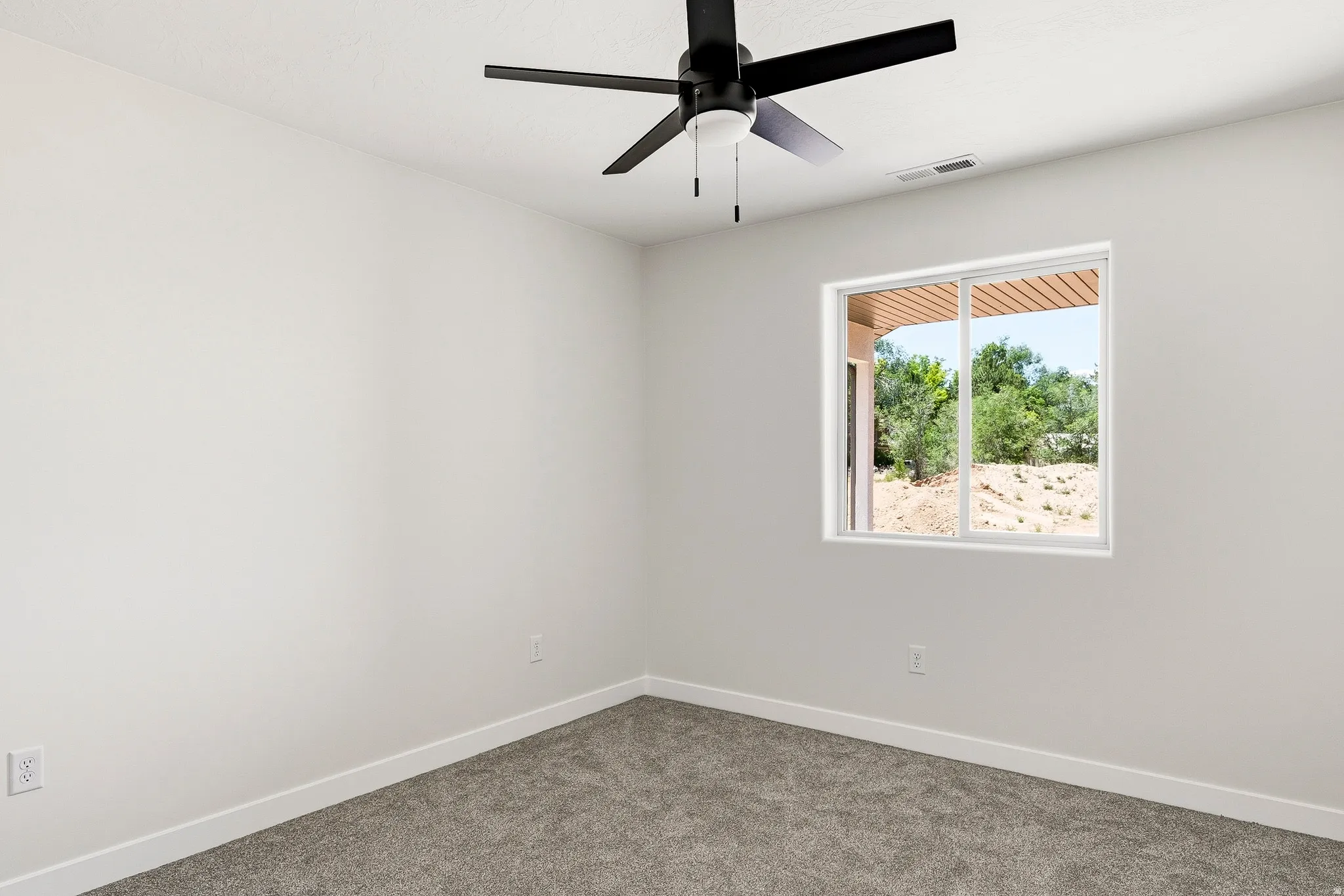 Recessed window with exterior scenery, overhead ceiling fan with light, light-toned walls, and carpeted flooring