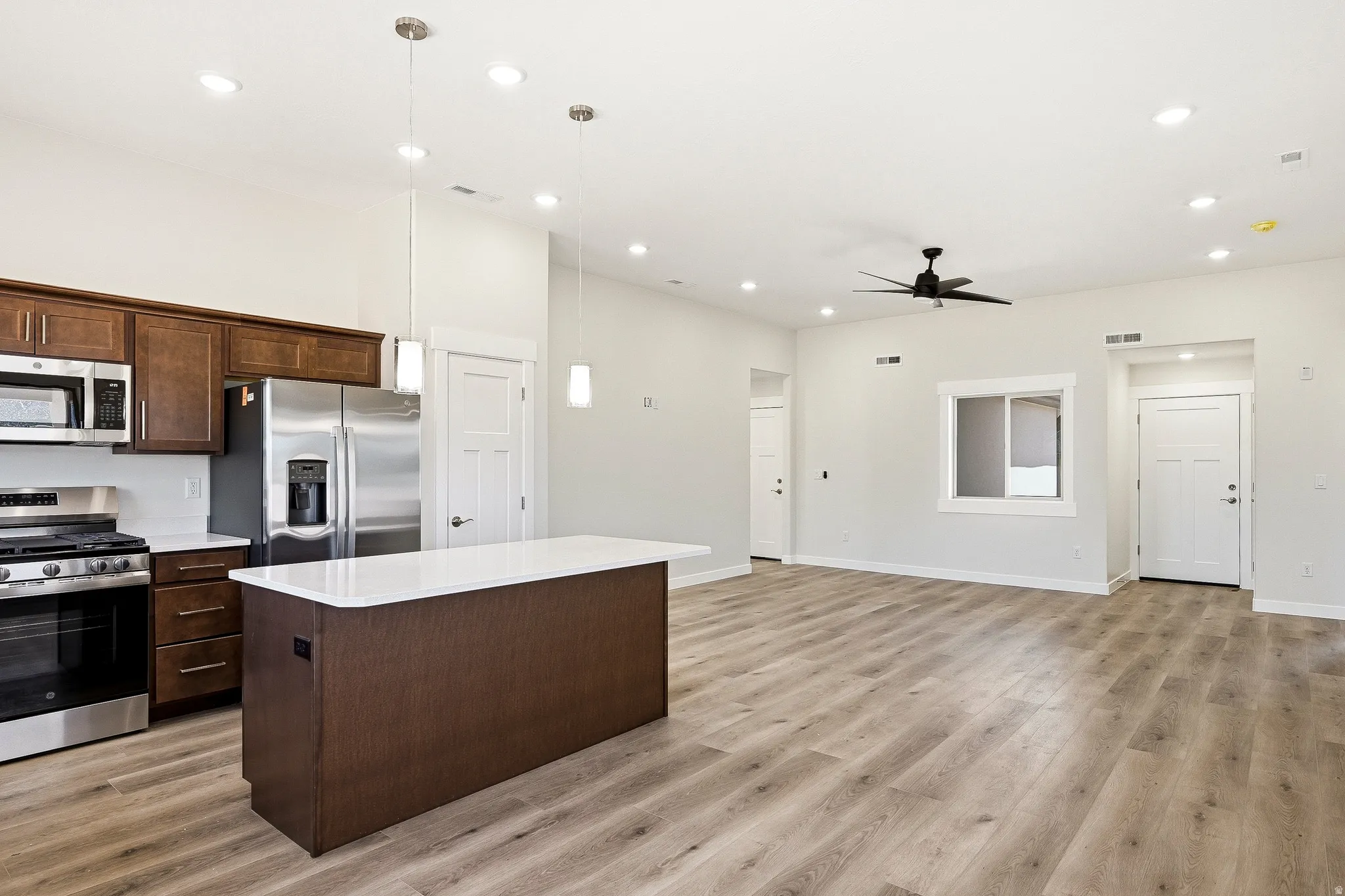 Open-concept living space with wood-finish flooring, recessed lighting, and a ceiling fan