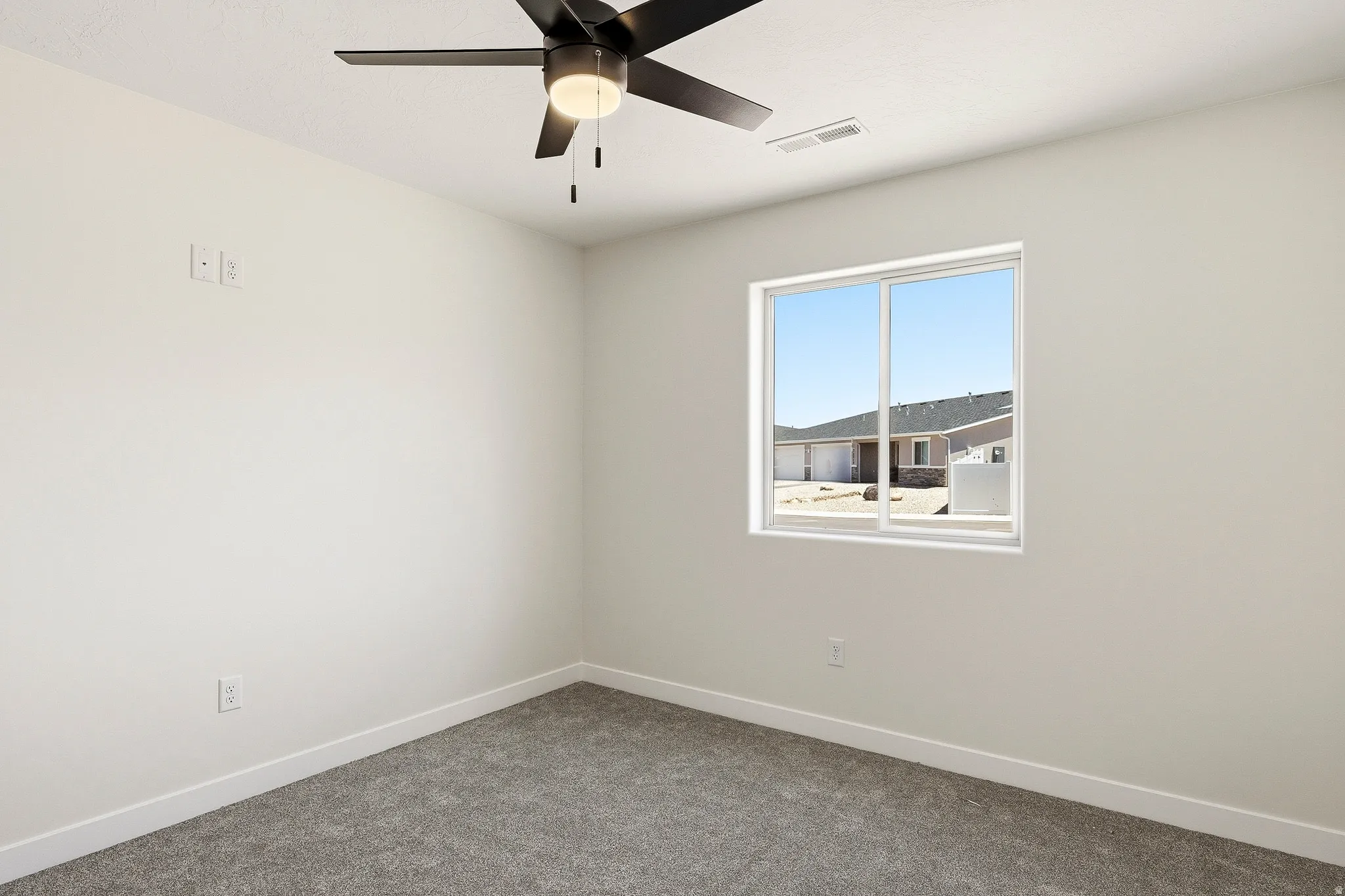 Recessed lighting, wall-mounted ceiling fan, neutral wall paint, gray carpet, and a white-framed window