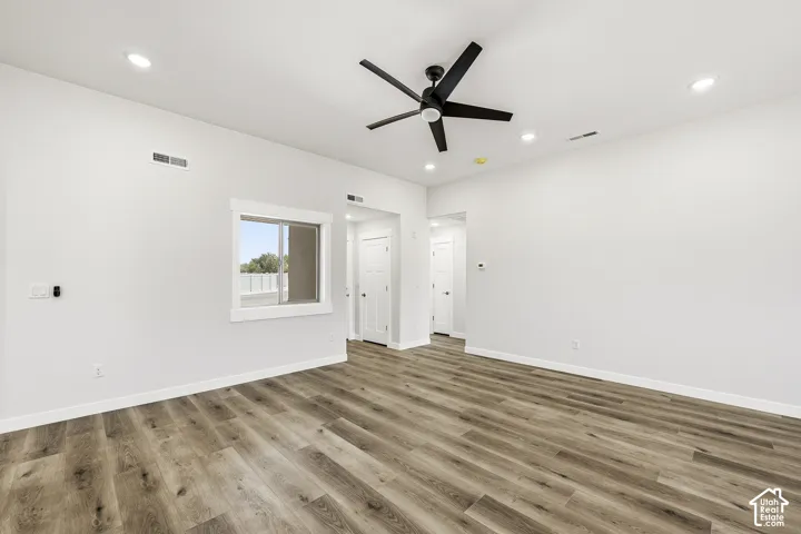 Bright, open room featuring wide-plank wood-finish flooring, recessed lighting, and a contemporary ceiling fan