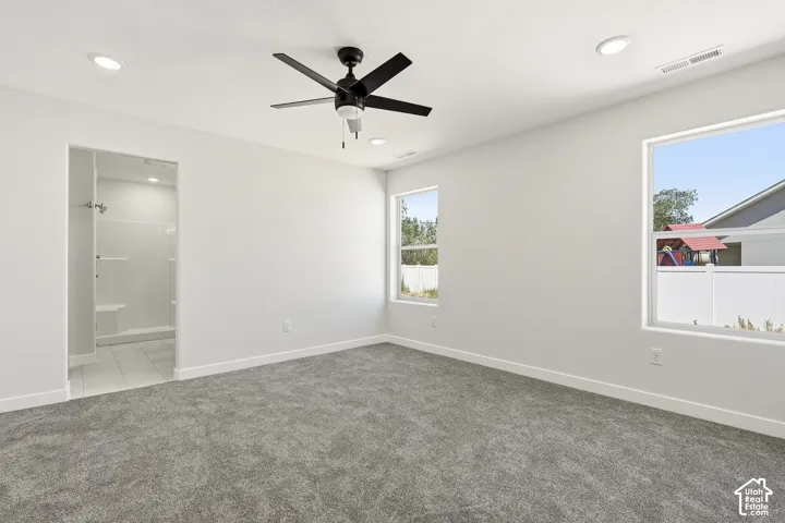 Recessed lighting, ceiling fan, two windows, wall-to-wall carpeting, and an adjacent tiled shower with a built-in bench