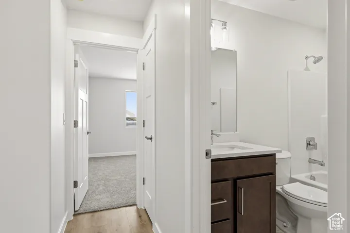 Wood-finish flooring, white walls, white doors, dark wood vanity, and a white sink