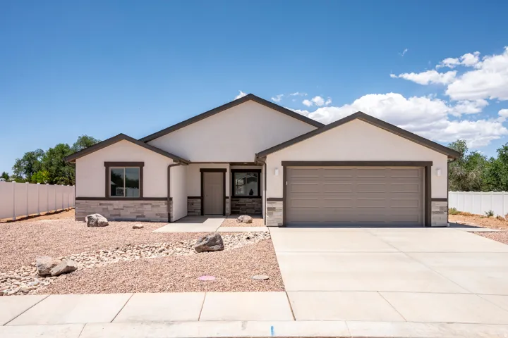 Contemporary stucco exterior featuring stone accents and a two-car garage