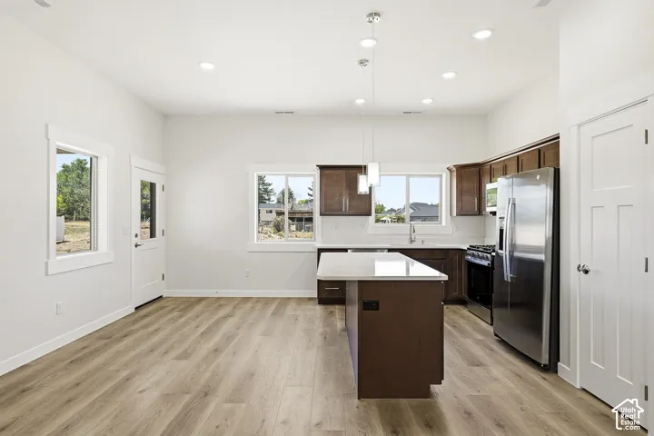 Open-concept kitchen with wood-finish flooring, stainless steel appliances, a center island, recessed lighting, and ample cabinetry