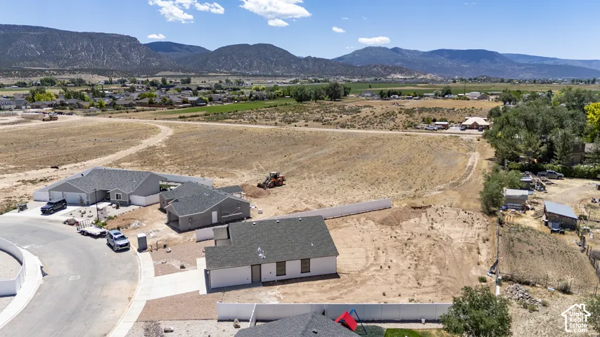 Expansive land parcel featuring existing residential structures, paved streets, and mountainous surroundings