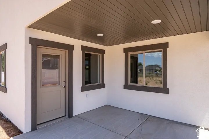 Covered patio featuring a concrete slab, recessed lighting, and a neutral-toned door with a glass insert