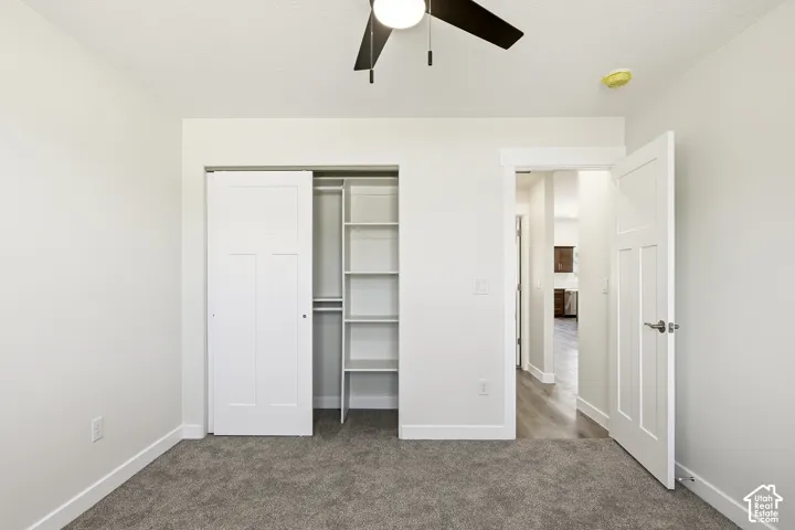 Built-in closet shelving, sliding closet doors, ceiling fan, carpeted flooring, and a flat-panel door with brushed nickel hardware