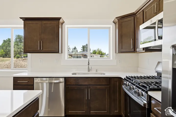 Kitchen featuring dark wood cabinetry, stainless steel appliances, a gas range, and white countertops
