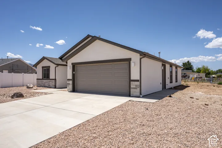 Stucco exterior with stone accents, attached garage, concrete driveway, and gravel landscaping