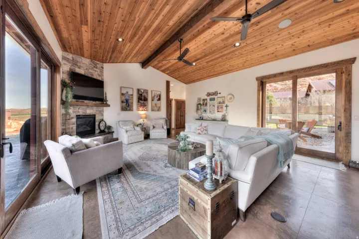 Living area featuring vaulted ceiling with beams, wooden ceiling, a fireplace, and ceiling fan