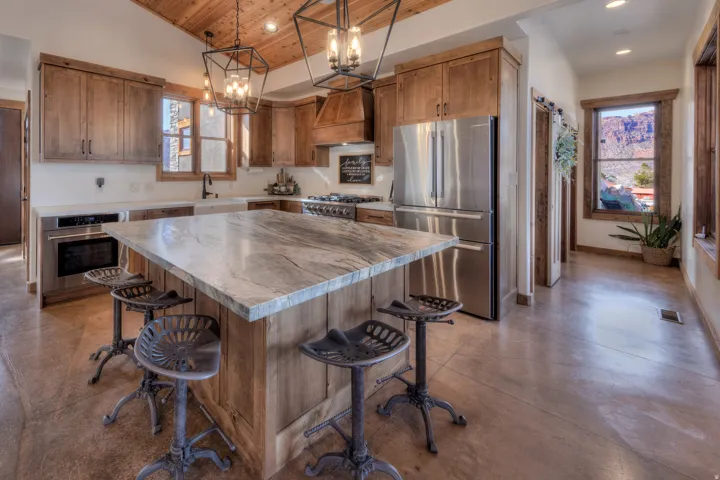 Kitchen with stainless steel appliances, concrete flooring, wood finish cabinetry, a kitchen island, and a breakfast bar