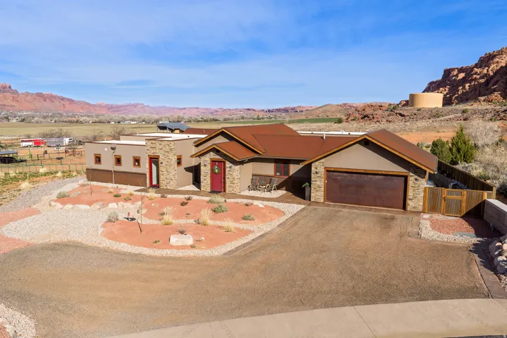 View of front of house with stone siding, driveway, a garage, and a mountain view