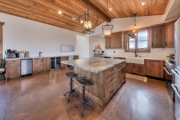 Kitchen featuring wood finish cabinetry, a center island, wine cooler, concrete flooring, and a breakfast bar
