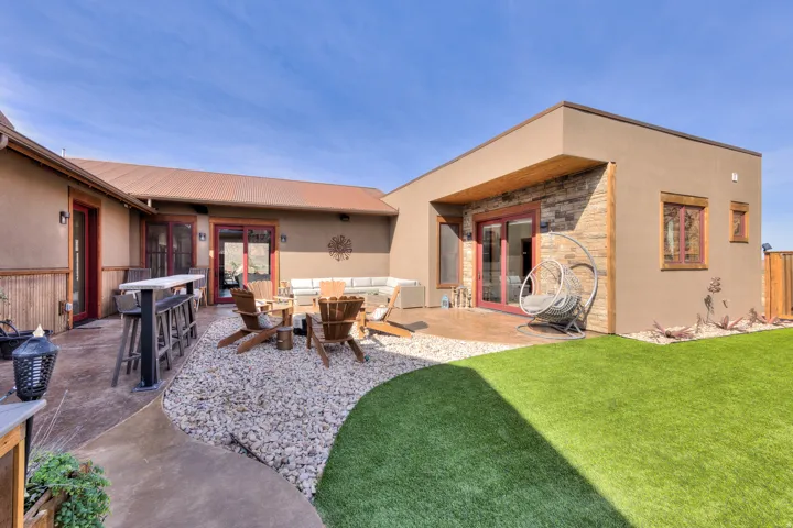 Rear view of property featuring french doors, a patio, stone siding, outdoor lounge area, and stucco siding