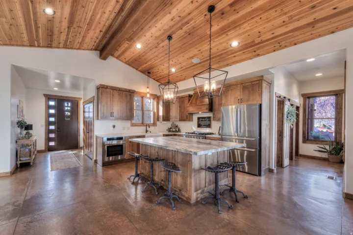 Kitchen featuring stainless steel appliances, a kitchen island, light countertops, finished concrete floors, and a kitchen breakfast bar
