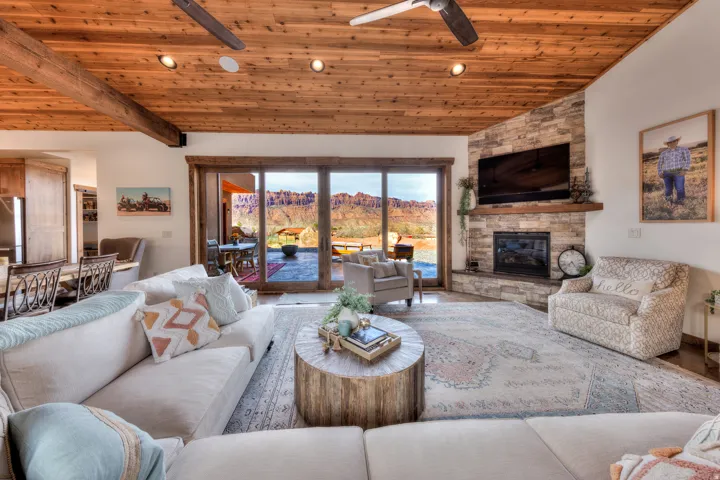 Living room with a ceiling fan, a vaulted wood ceiling, a stone fireplace, and recessed lighting