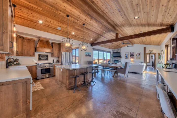 Kitchen with concrete floors, open floor plan, a kitchen island, stainless steel appliances, and a high wooden beamed ceiling