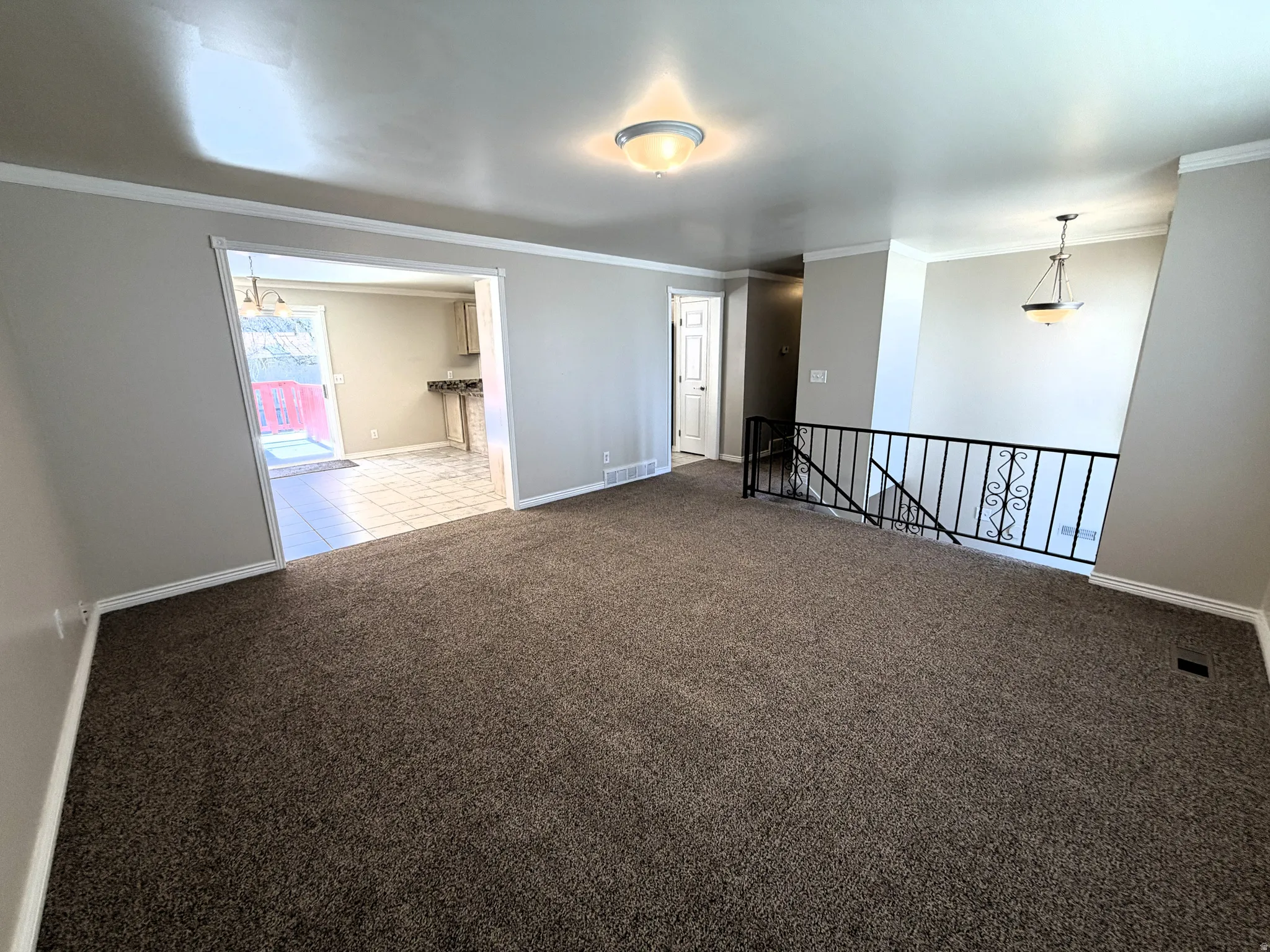 Carpeted front room featuring ornamental molding and baseboards