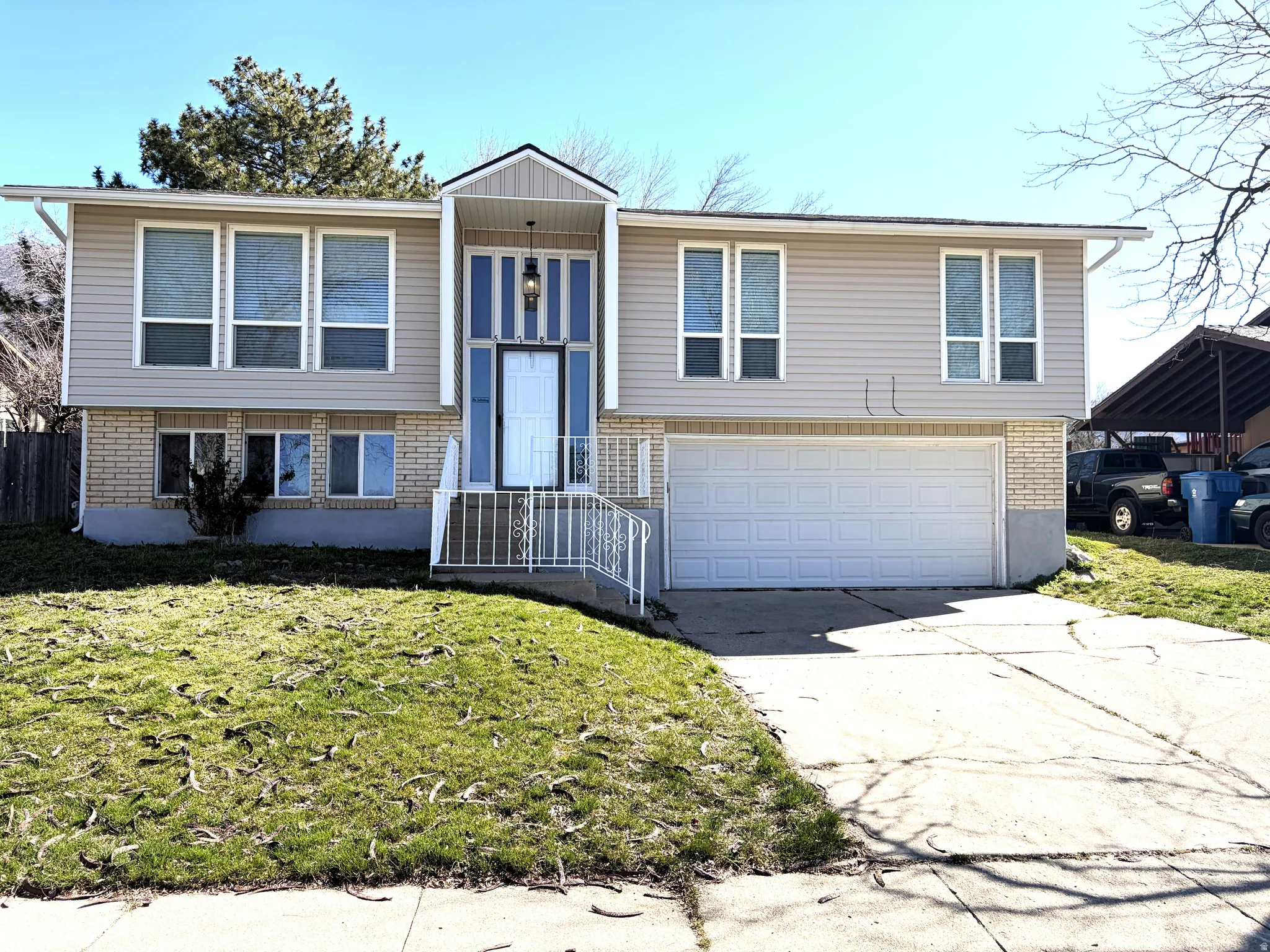Raised ranch with a front yard, an attached garage, brick siding, and driveway