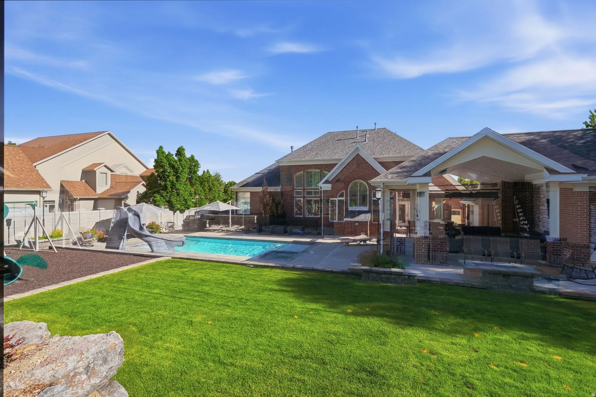 Expansive green lawn bordering a concrete patio with an in-ground swimming pool