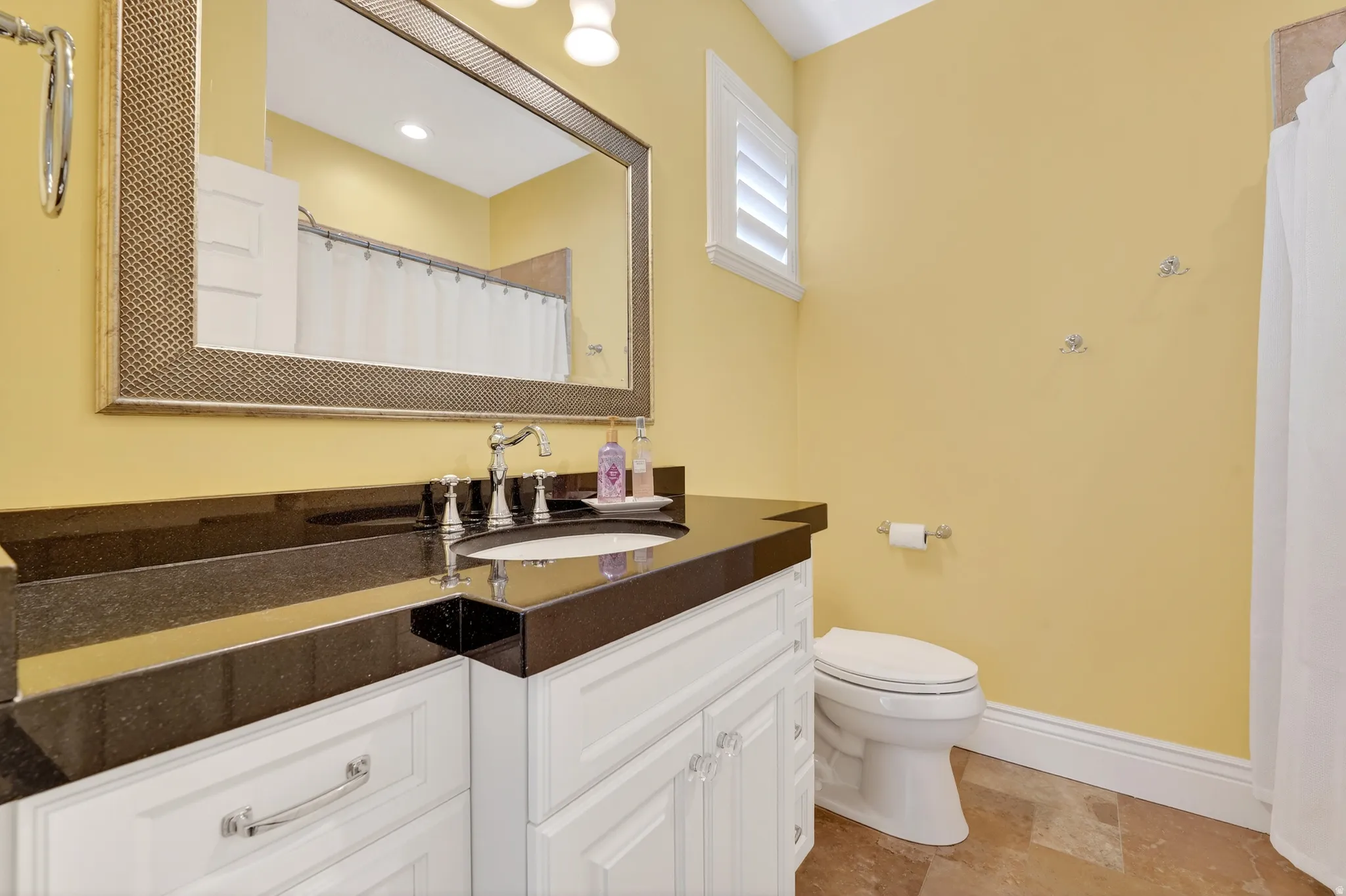 Full bath featuring vanity, a shower with curtain, and light stone finish floors