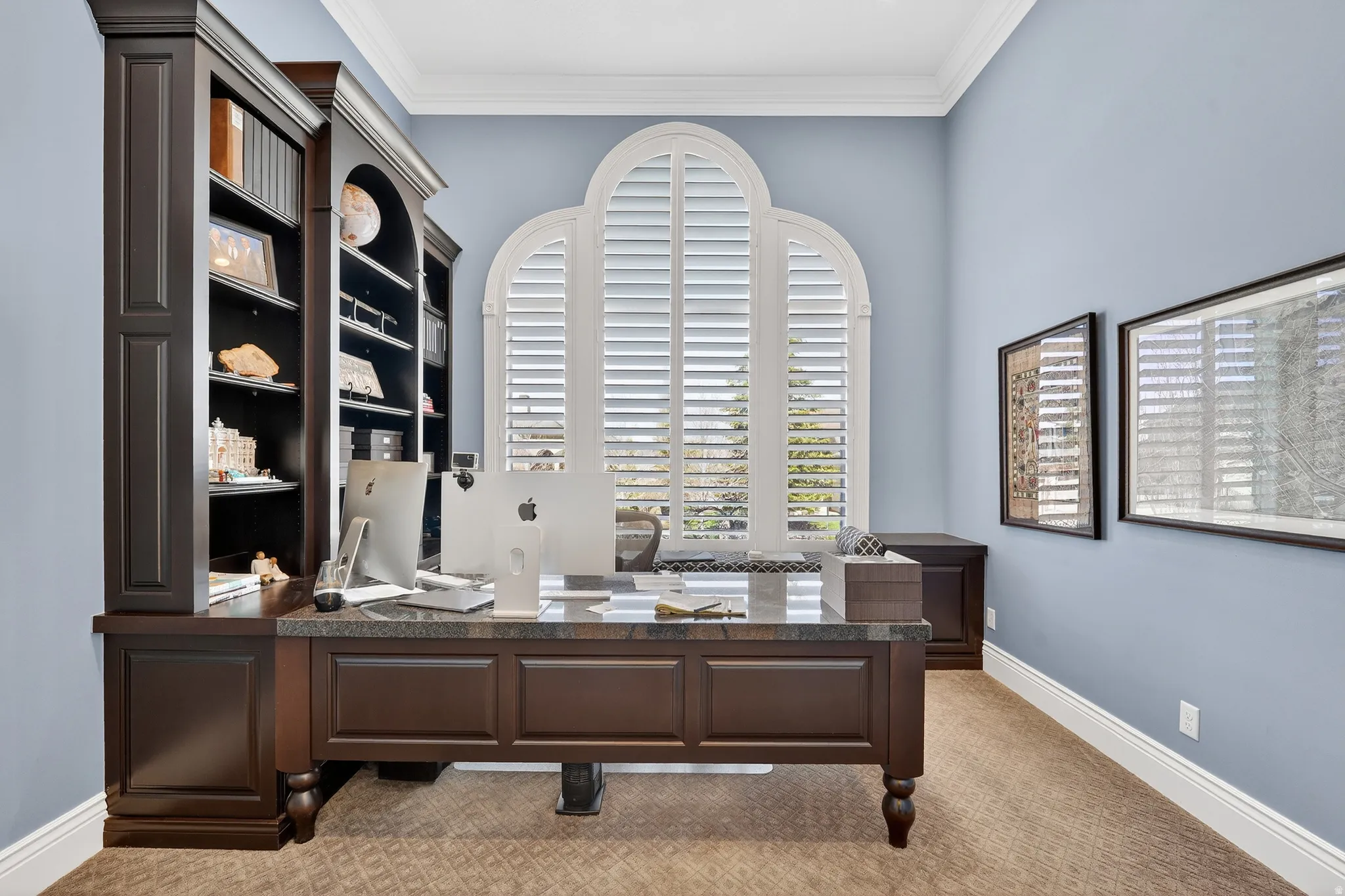 Office space featuring light carpet, built in desk and cabinets and crown molding
