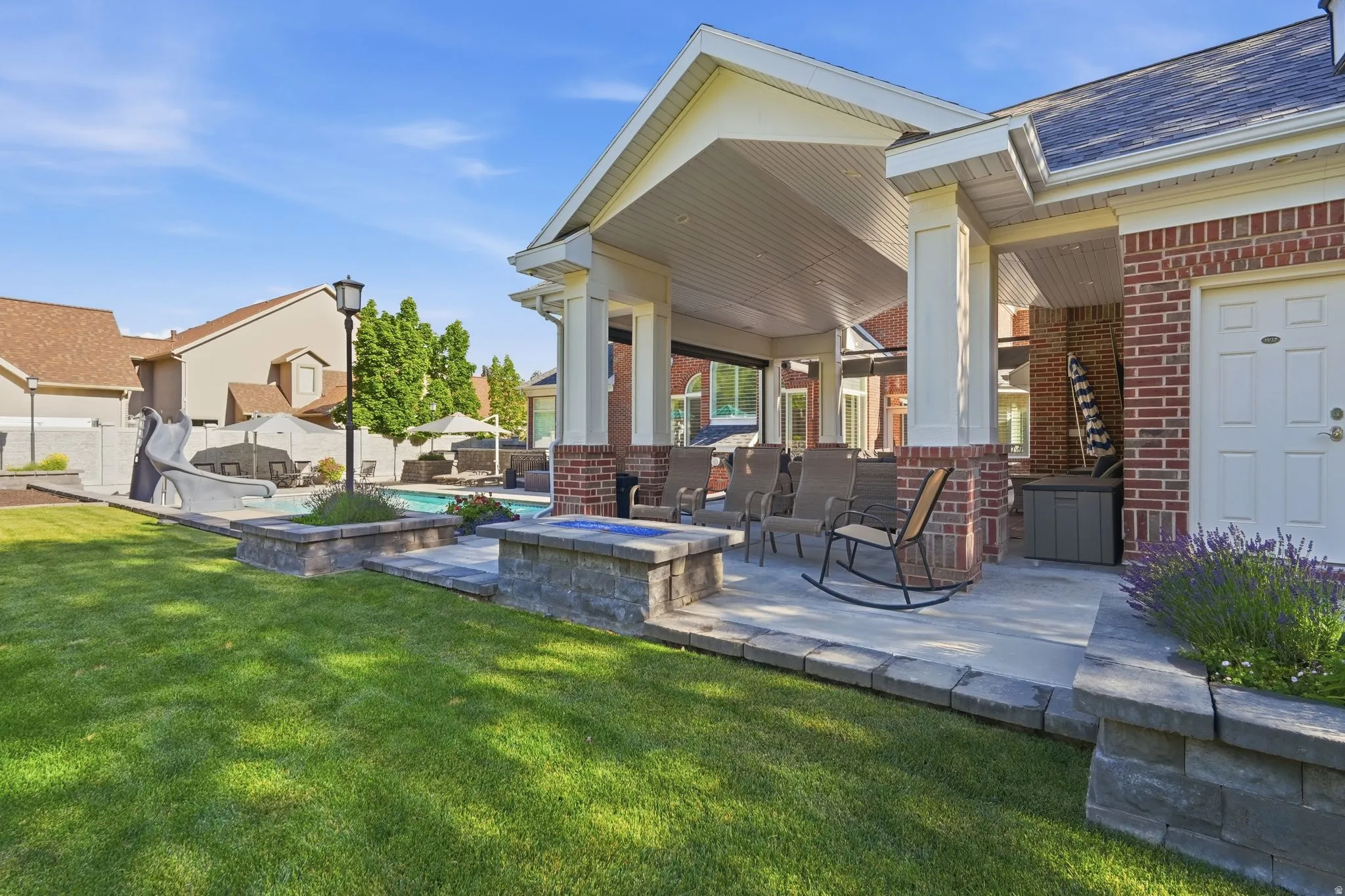 Expansive patio area featuring a covered porch with white columns, a brick exterior wall, and a white door