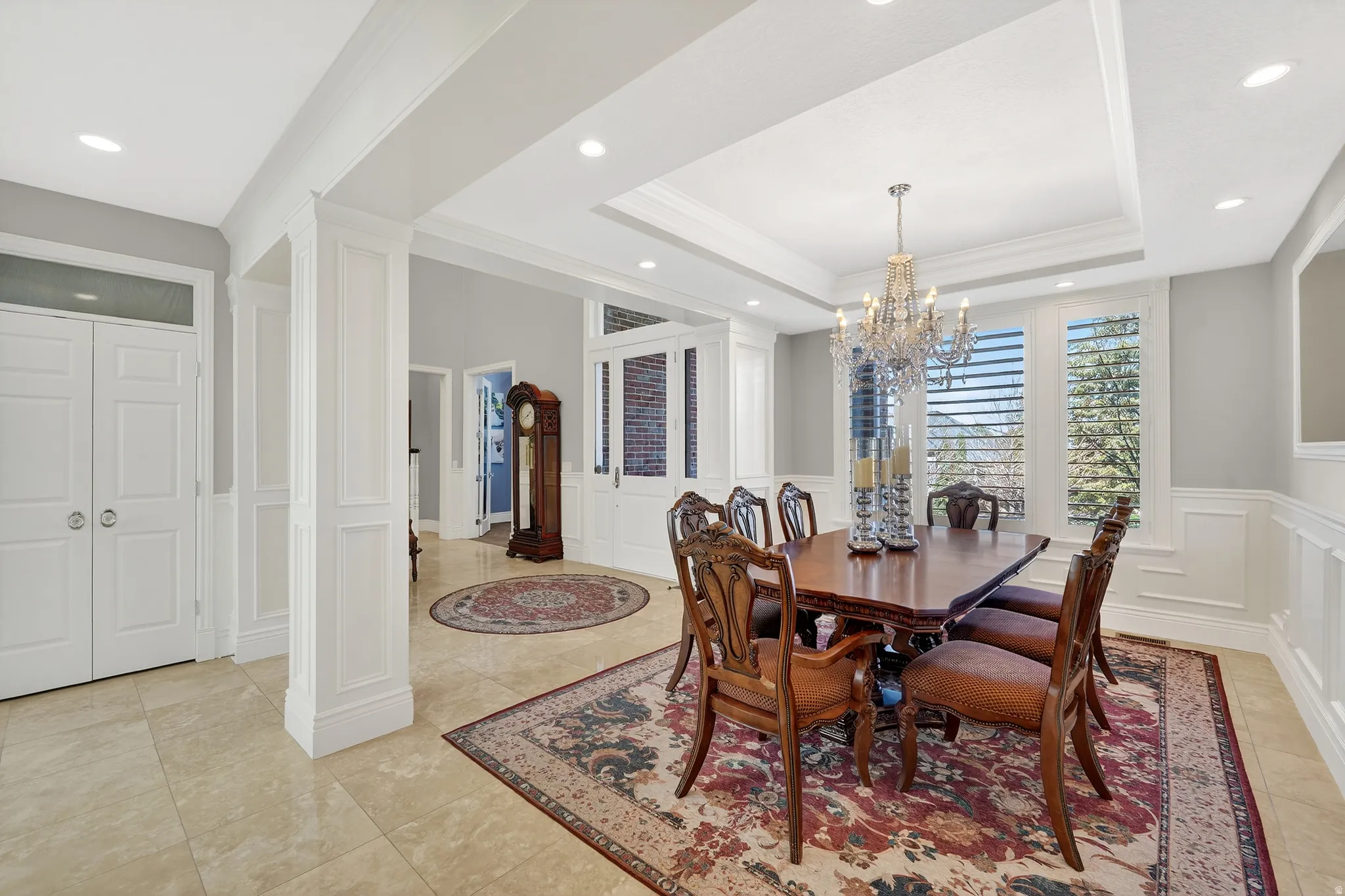 Formal Dining area with crown molding, a decorative wall, a wainscoted wall, suspended lighting, and a raised ceiling