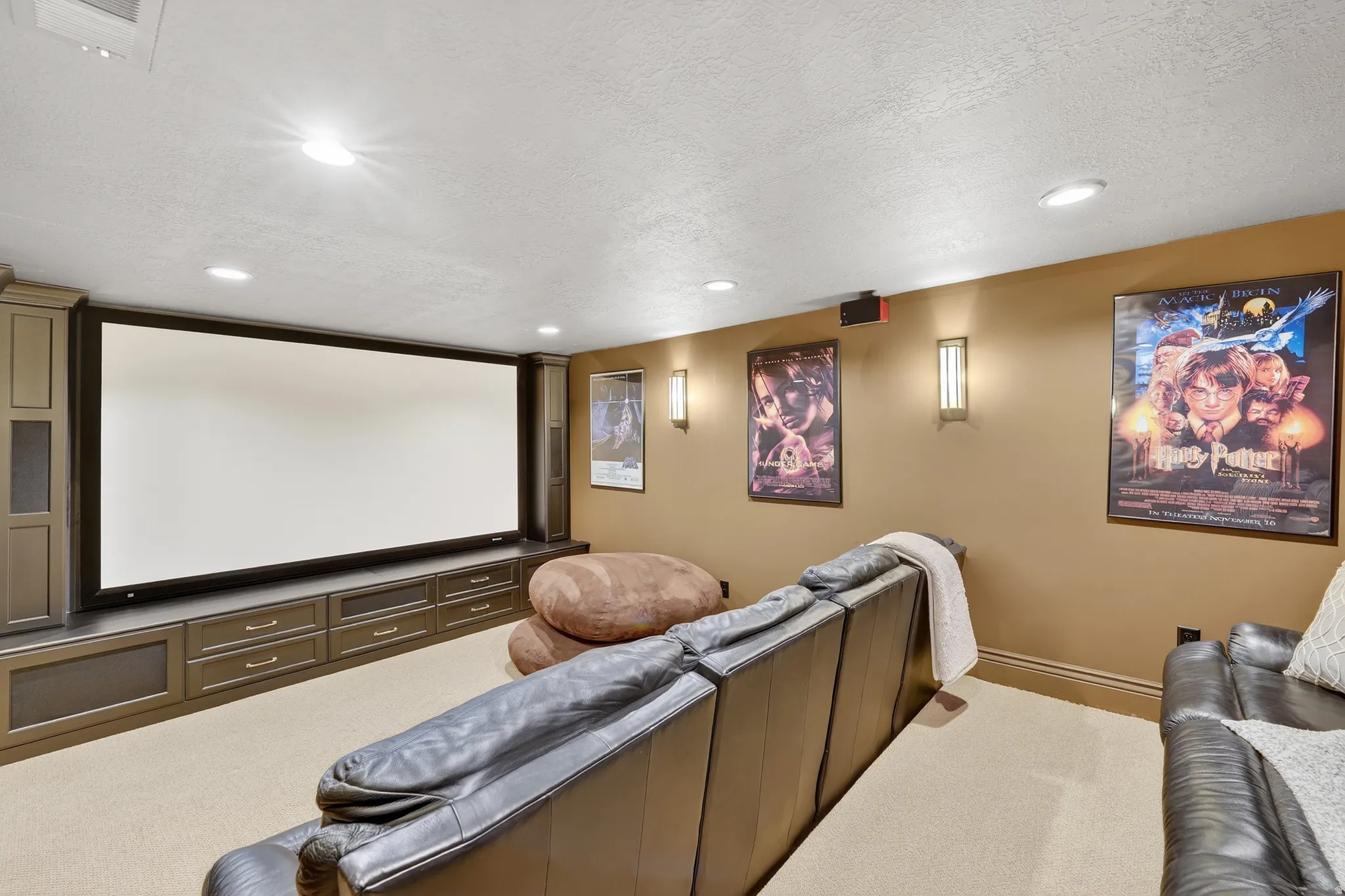 Carpeted cinema room with a textured ceiling and recessed lighting