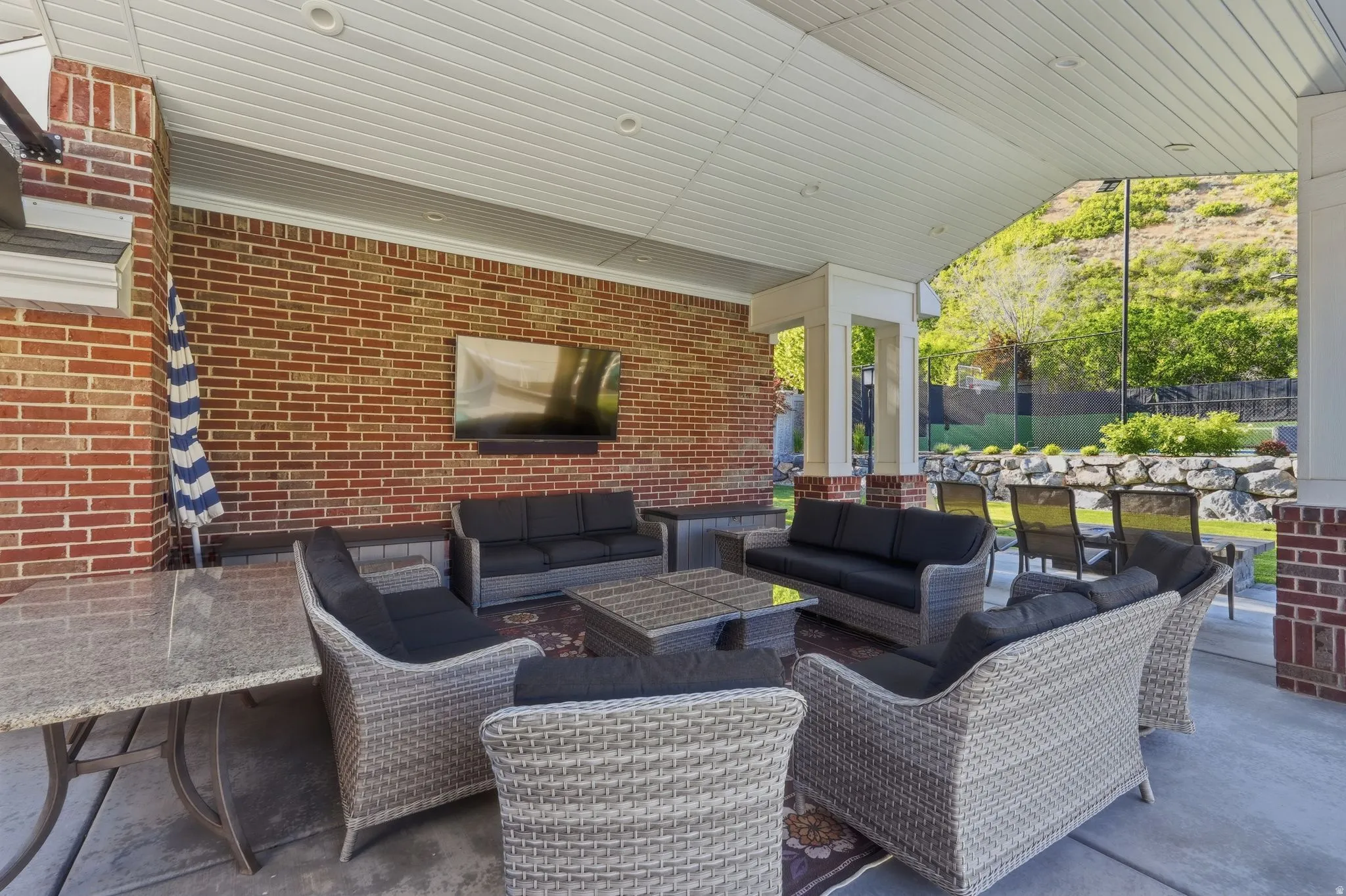 Covered patio area featuring a brick accent wall, recessed lighting, and a built-in entertainment system
