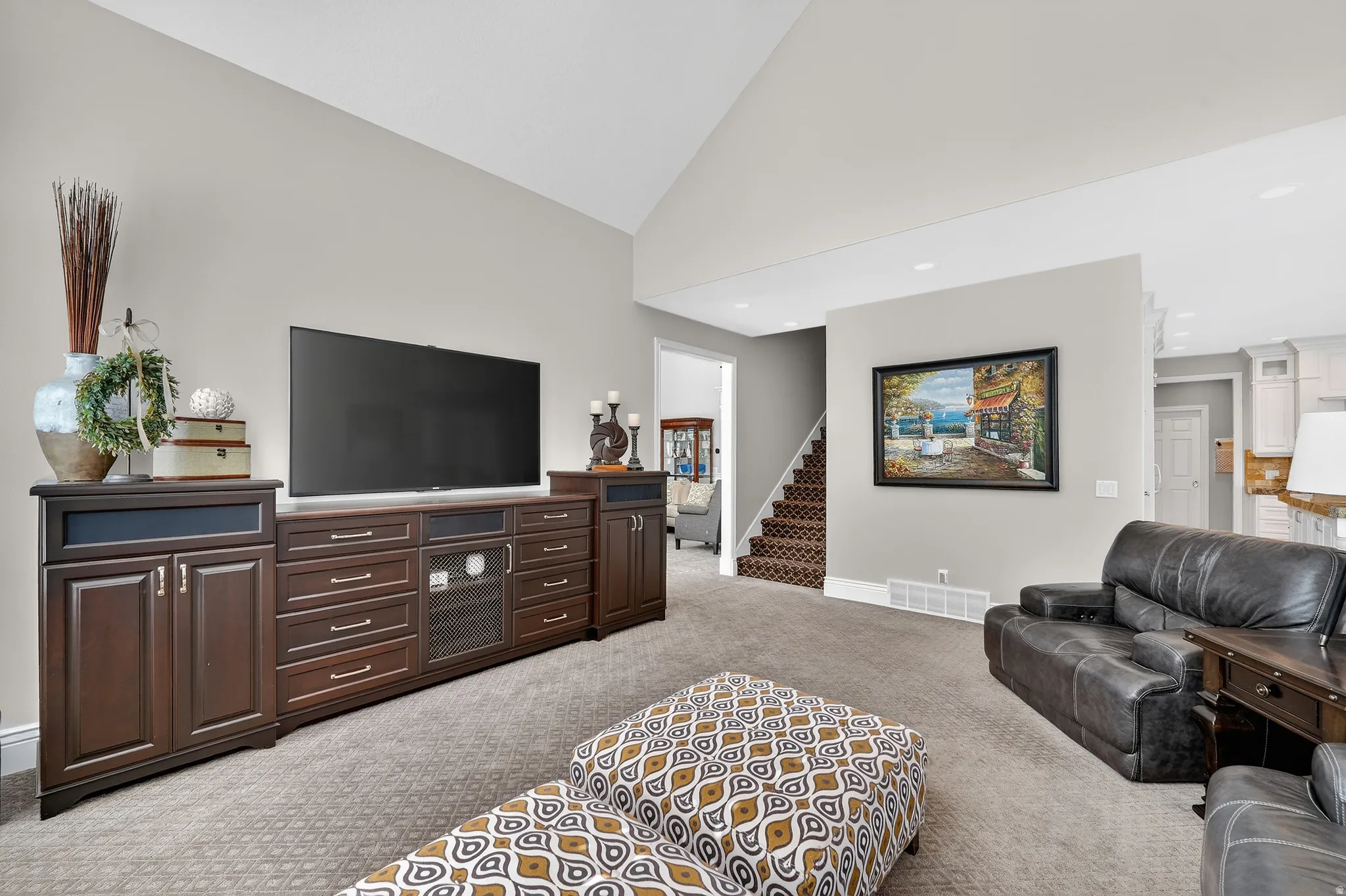 Family room with light carpet, built in cabinets, and vaulted ceiling