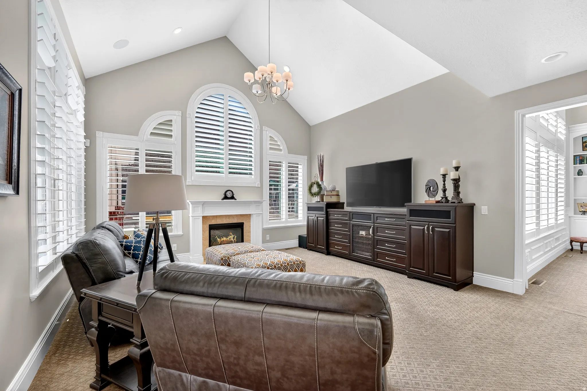 Family Room area featuring built in cabinets, light carpet, a high ceiling, a fireplace, and hanging lights