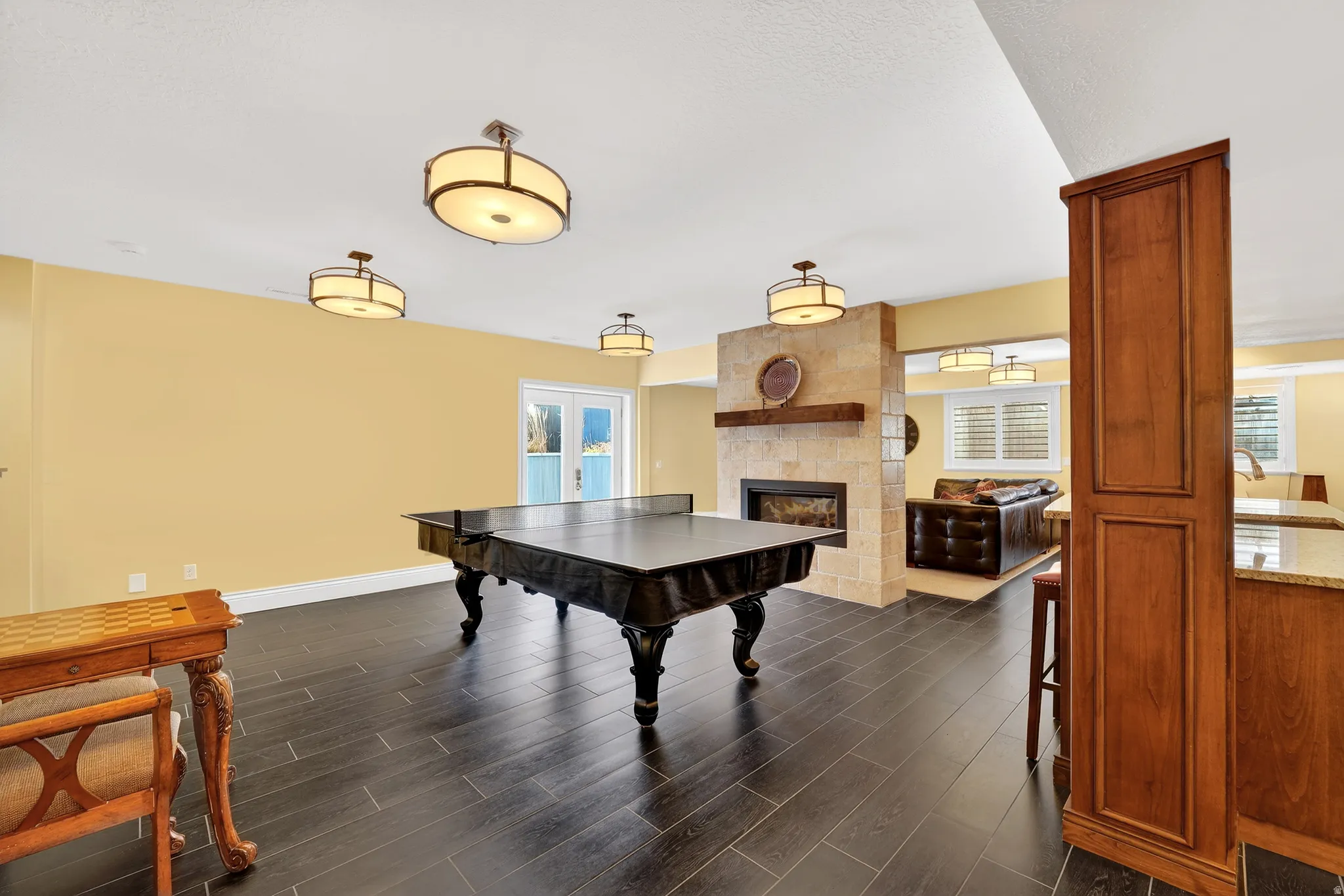 Rec room with dark wood-style floors and a large fireplace