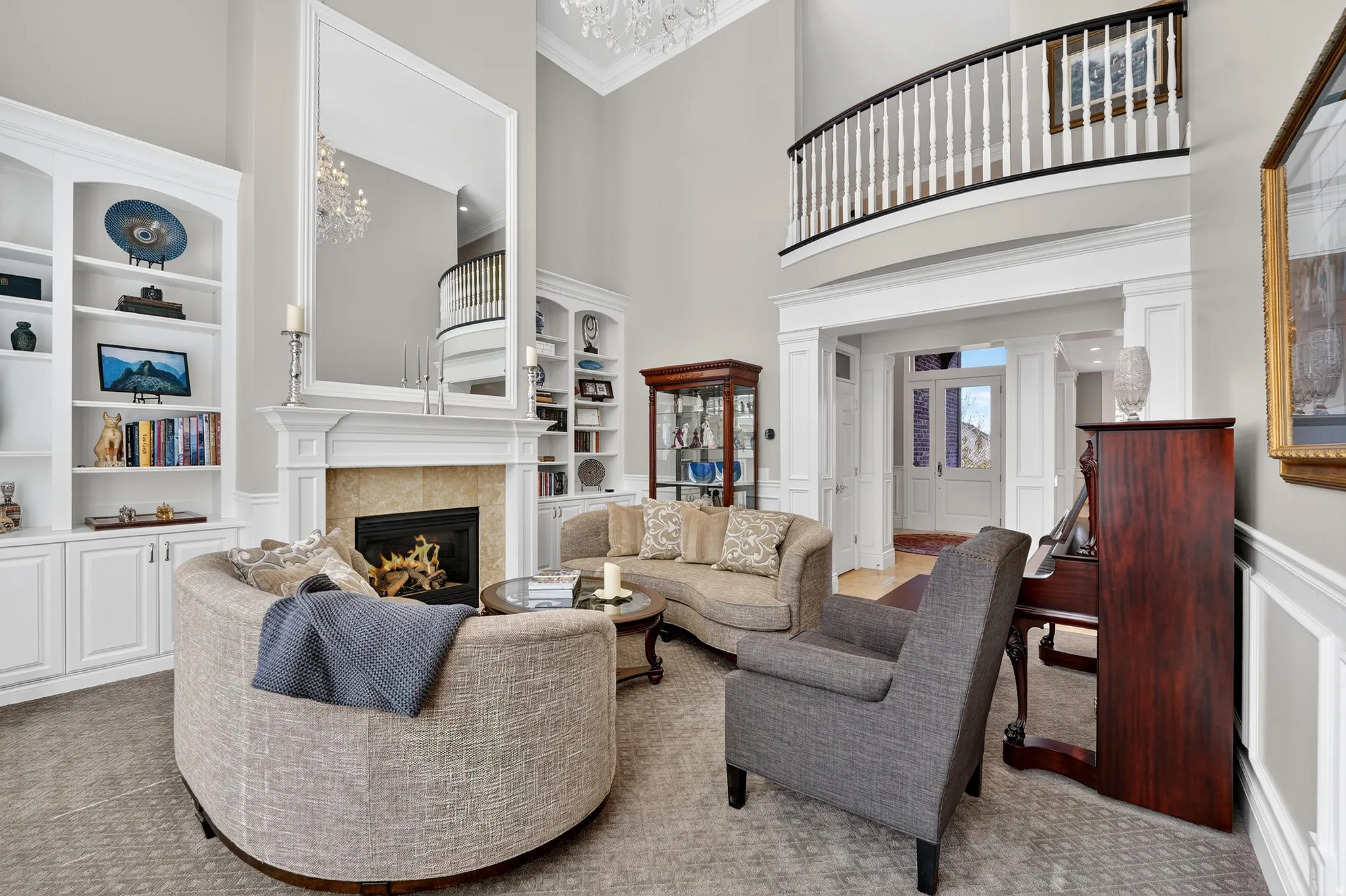 Carpeted living room featuring built in shelves, a high ceiling, a wainscoted wall, crown molding, and a decorative wall
