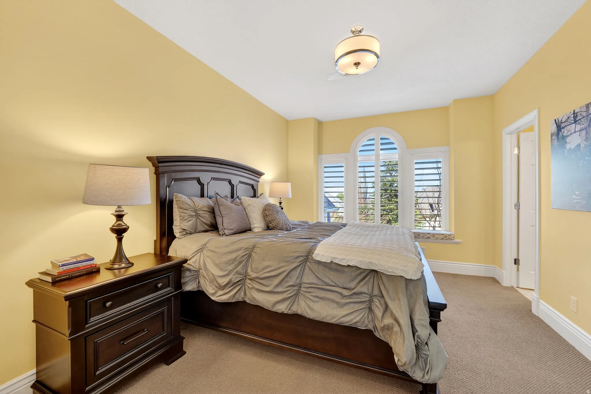 Bedroom featuring baseboards, en-suite bathroom and light carpet