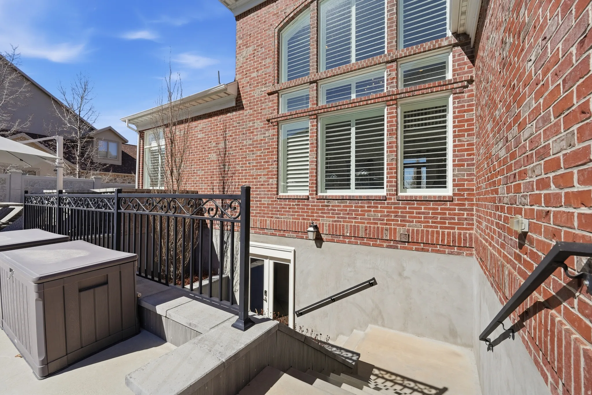 View of side of home with brick siding, a deck, and a patio