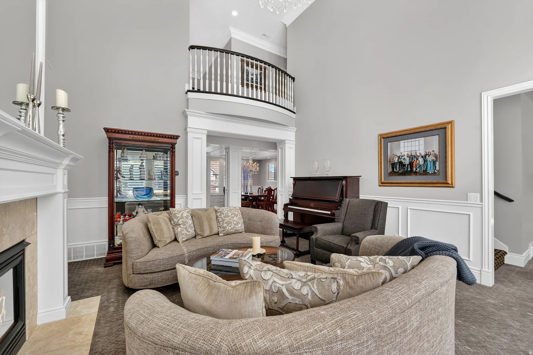 Living area with a high ceiling, crown molding, a fireplace, decorative columns, and a chandelier