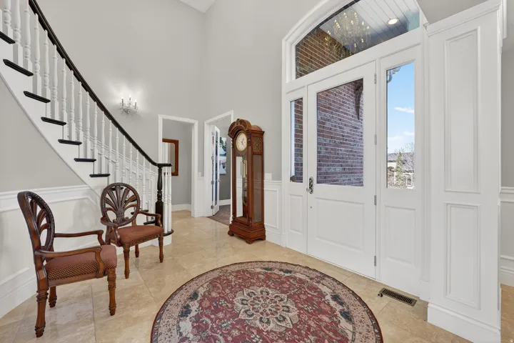 Foyer featuring a decorative wall, a wainscoted wall, and a high ceiling