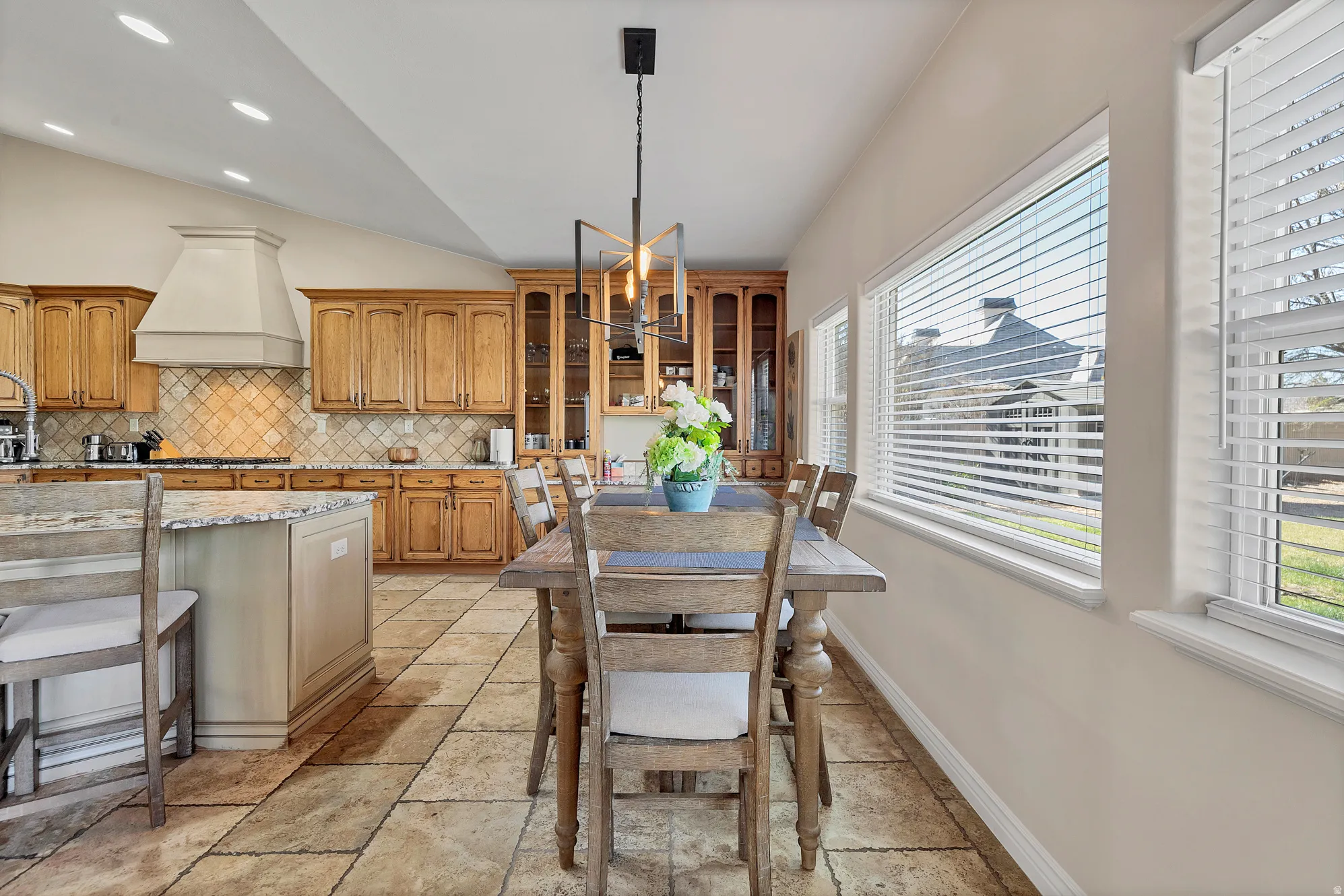 Dining room with vaulted ceiling, stone tile flooring, and recessed lighting