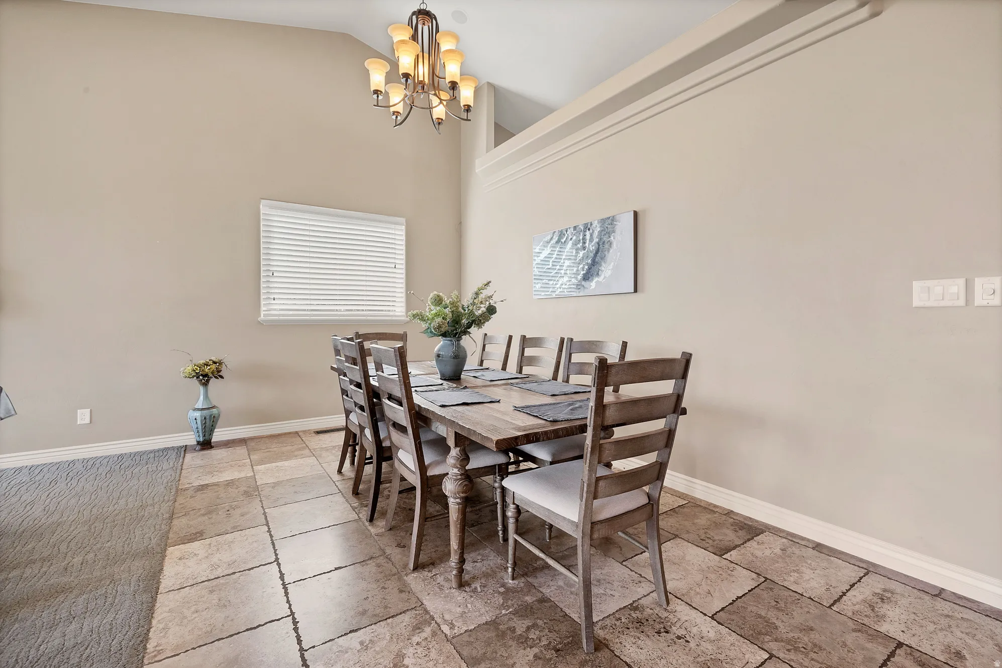 Dining room featuring stone tile floors, suspended lighting, and lofted ceiling