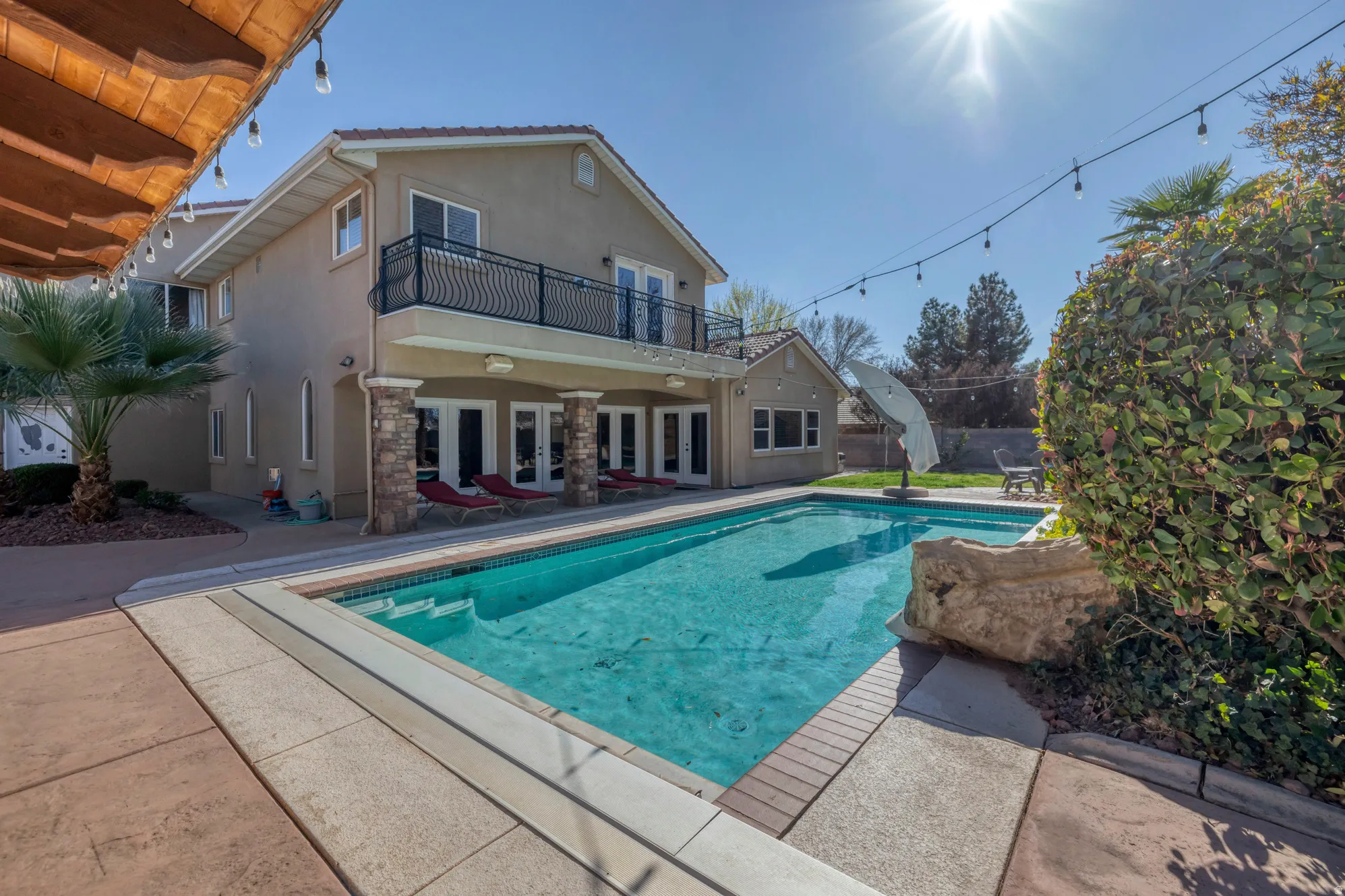 Outdoor pool with a patio, french doors, and a balcony