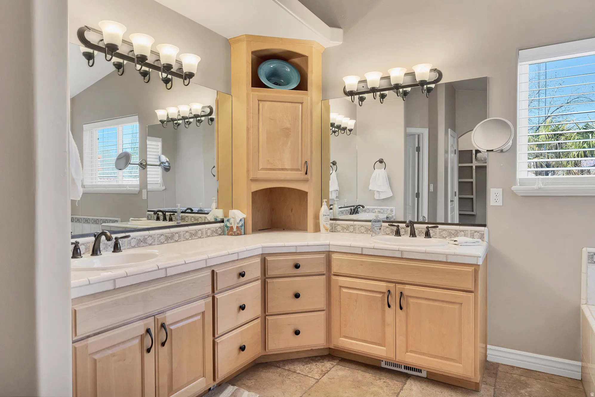 Full bathroom featuring double vanity, plenty of natural light, a garden tub, and lofted ceiling