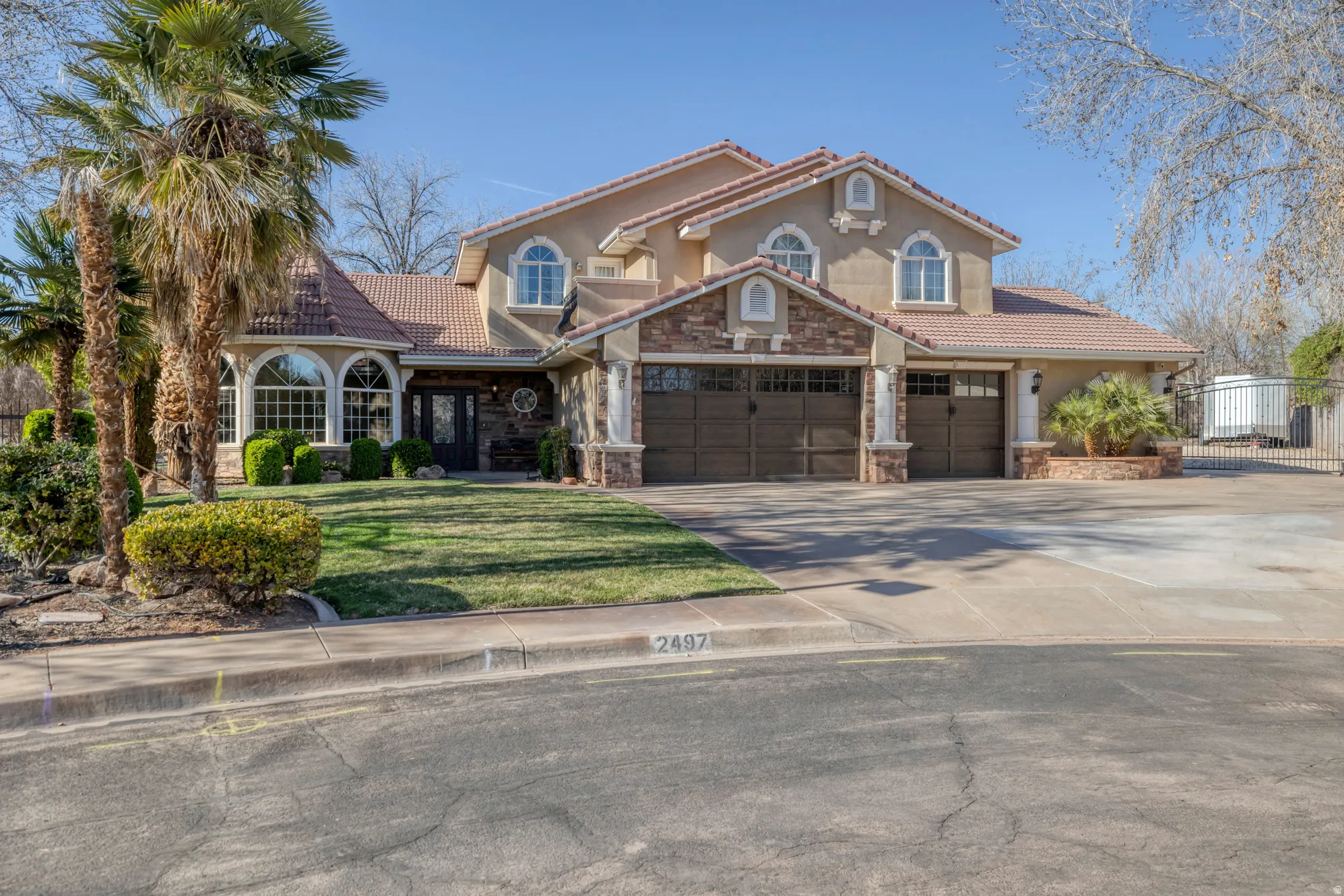 Mediterranean / spanish house with a tile roof, driveway, stone siding, stucco siding, and a garage