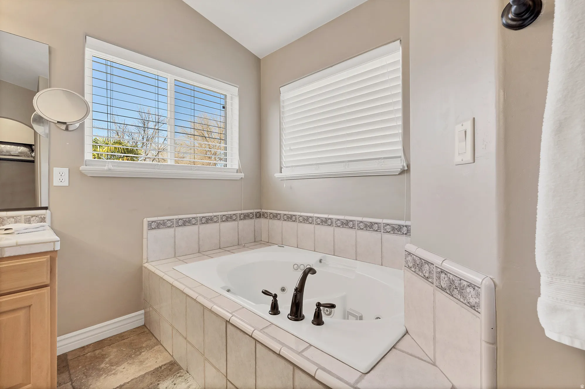 Bathroom with a jetted tub, vanity, and vaulted ceiling