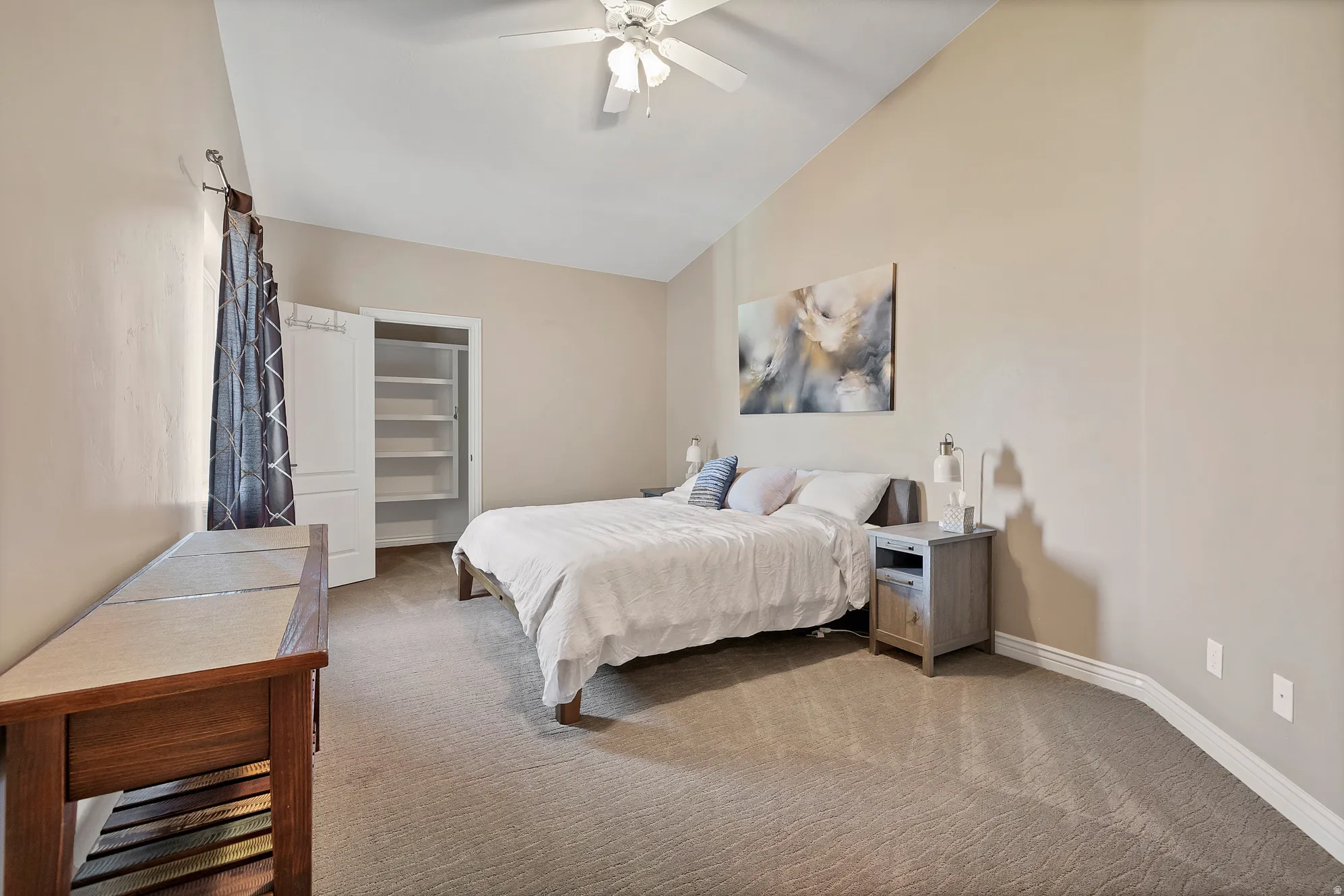 Carpeted bedroom featuring ceiling fan and lofted ceiling