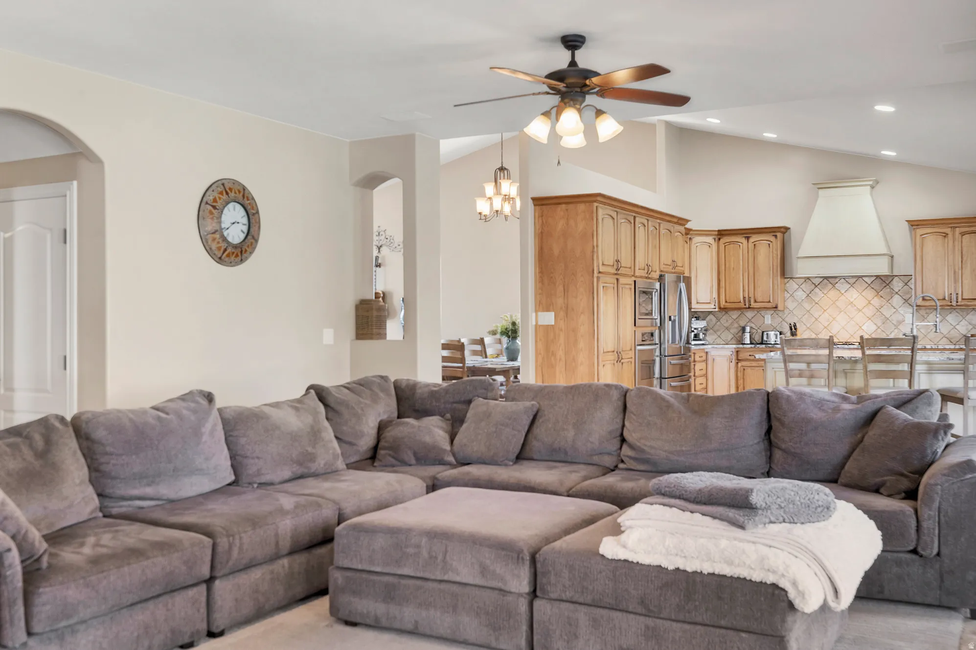 Living area with lofted ceiling, ceiling fan, arched walkways, and recessed lighting